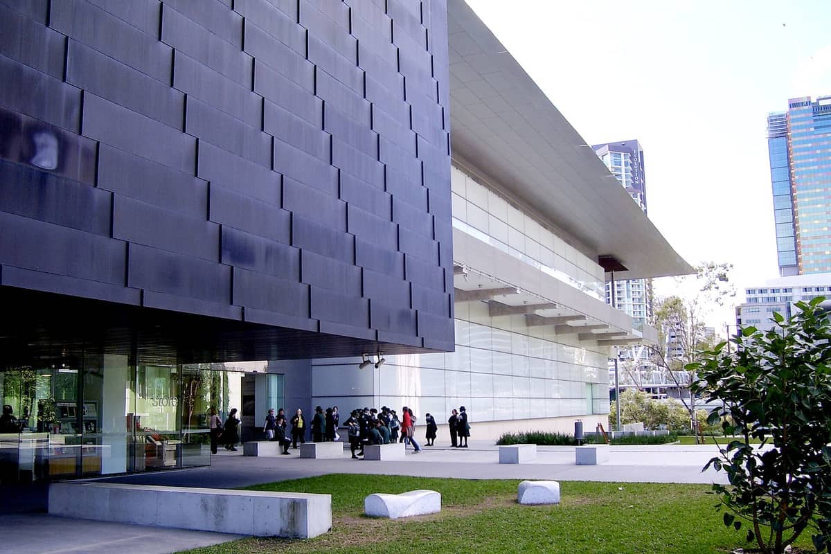 Exterior view of Gallery of Modern Art (GOMA) in Brisbane, showing its modern architecture, glass façade, and groups of visitors outside.