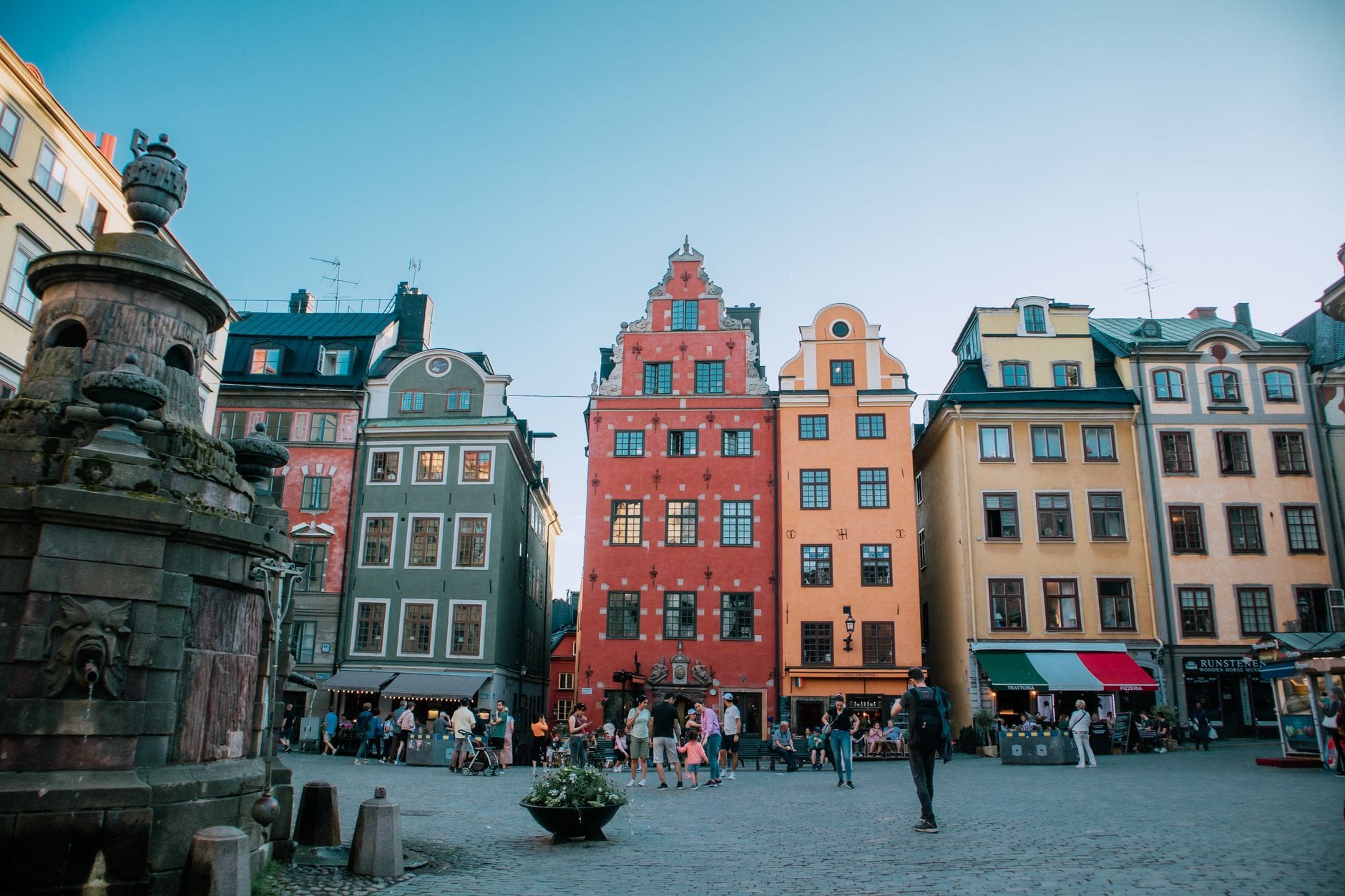 อาคารเก่าแก่สีสันสดใสและจัตุรัส Stortorget ใจกลาง Gamla Stan เมืองเก่าสต็อกโฮล์ม คนเดินเล่นและนั่งเล่นกลางแจ้ง