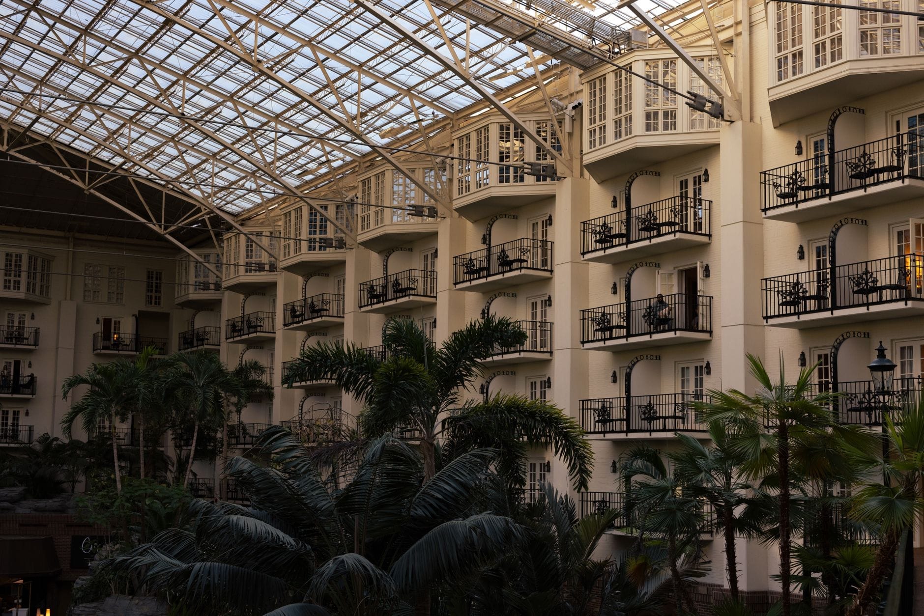 Vista interior del Gaylord Opryland Resort con balcones que dan a exuberantes jardines interiores con palmeras bajo el techo de cristal del atrio.