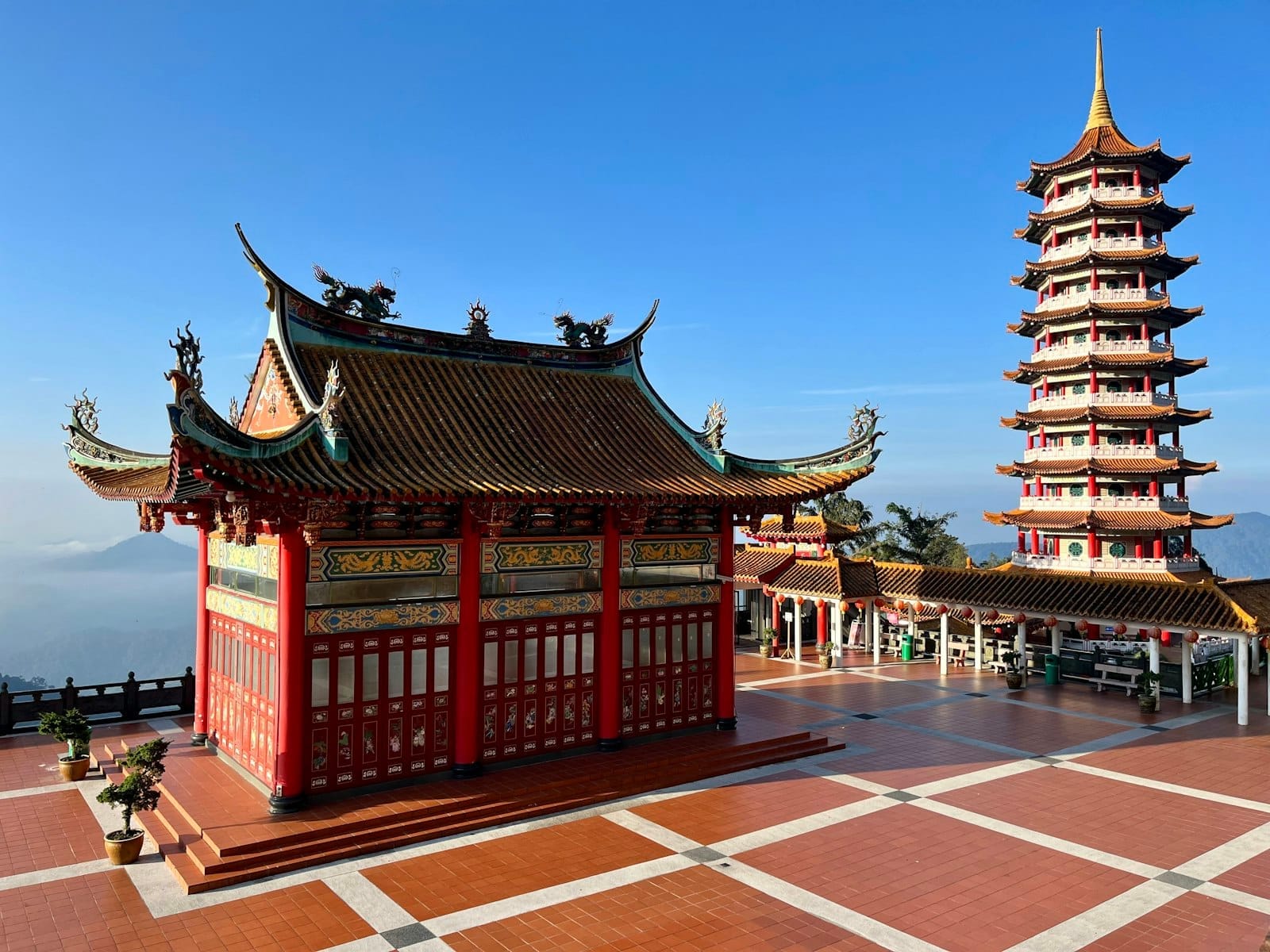 Chin Swee Caves Temple at Genting Highlands featuring ornate roofs, vibrant red walls, and a tall pagoda under clear blue sky.