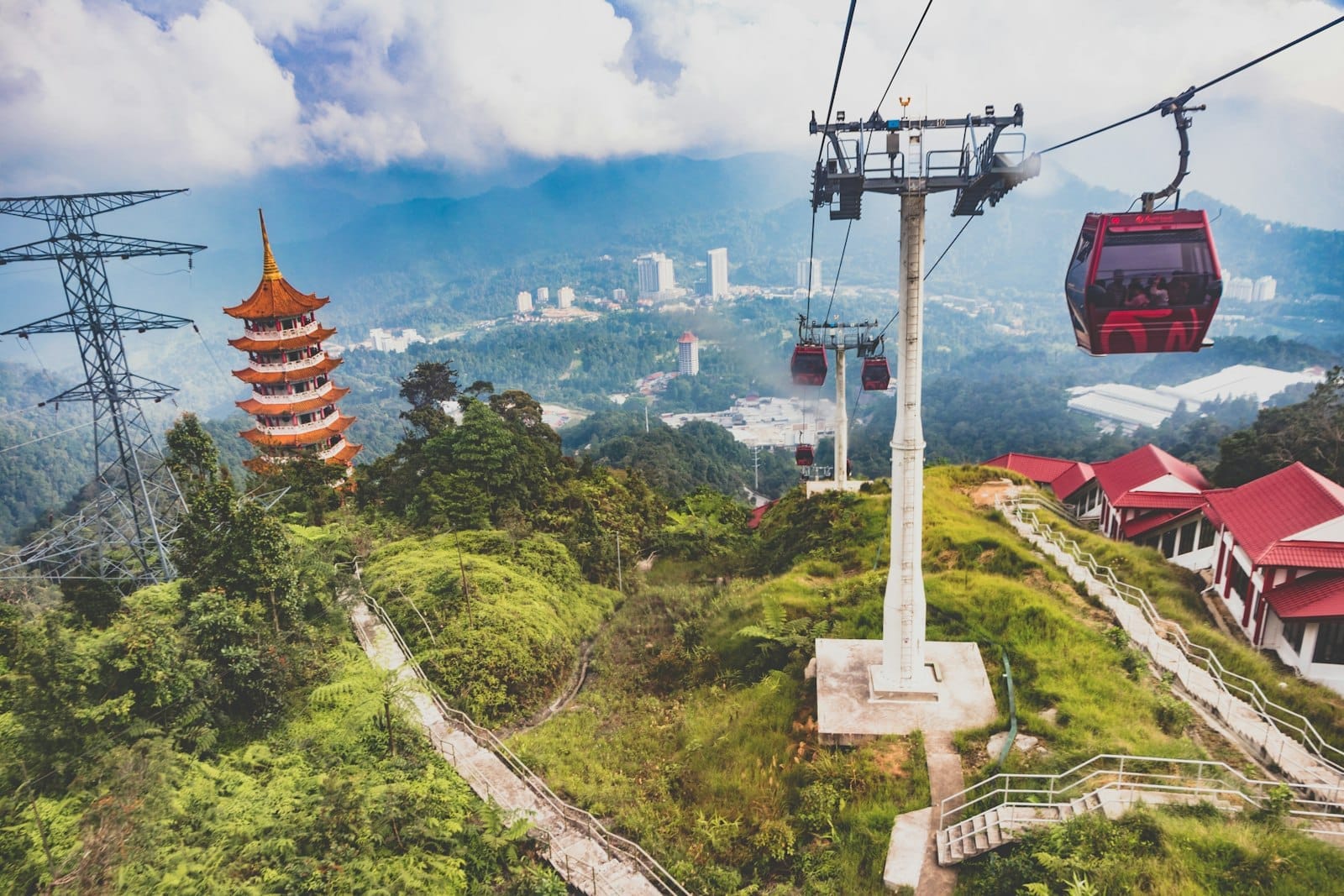 Misty mountains and vibrant red gondolas float above Genting Highlands, offering visitors a tranquil escape surrounded by lush greenery and unique architecture.