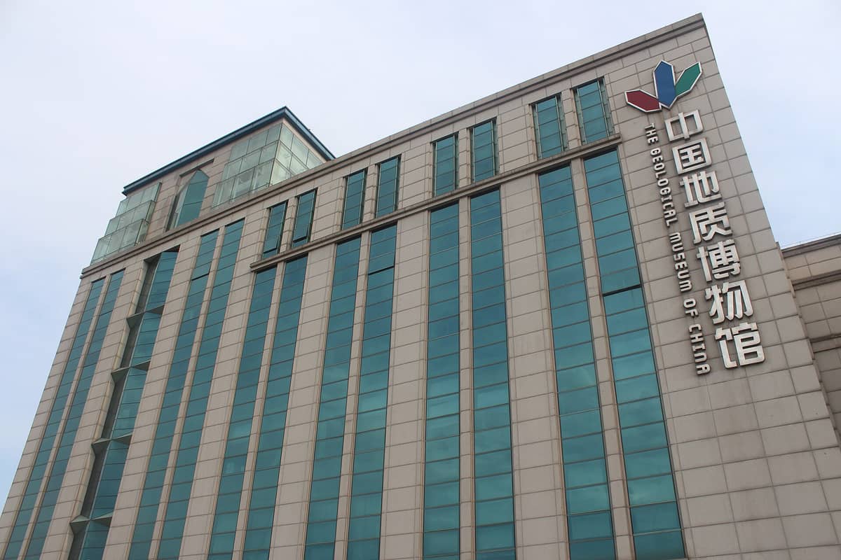 Hohes modernes Gebäude mit blauen Glasfenstern und großem Schriftzug „Geologisches Museum Chinas" an der Fassade.