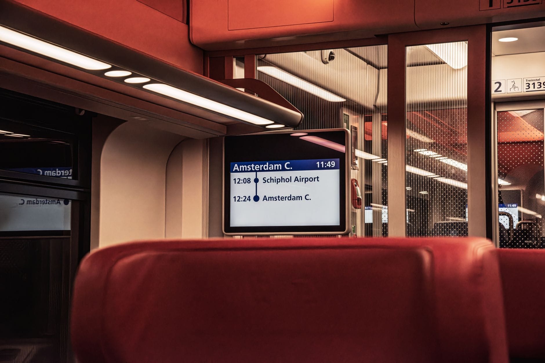 Interior de un tren con pantalla digital que muestra la ruta desde el Aeropuerto de Schiphol hasta la Estación Central de Ámsterdam.