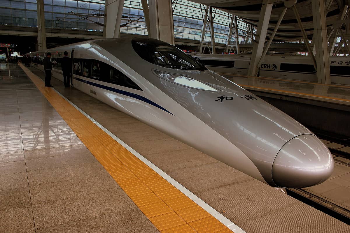 Chinesischer Hochgeschwindigkeitszug auf einem modernen Bahnsteig mit Beschilderung und großen Fenstern, bereit zur Abfahrt zwischen Städten ab Beijing.