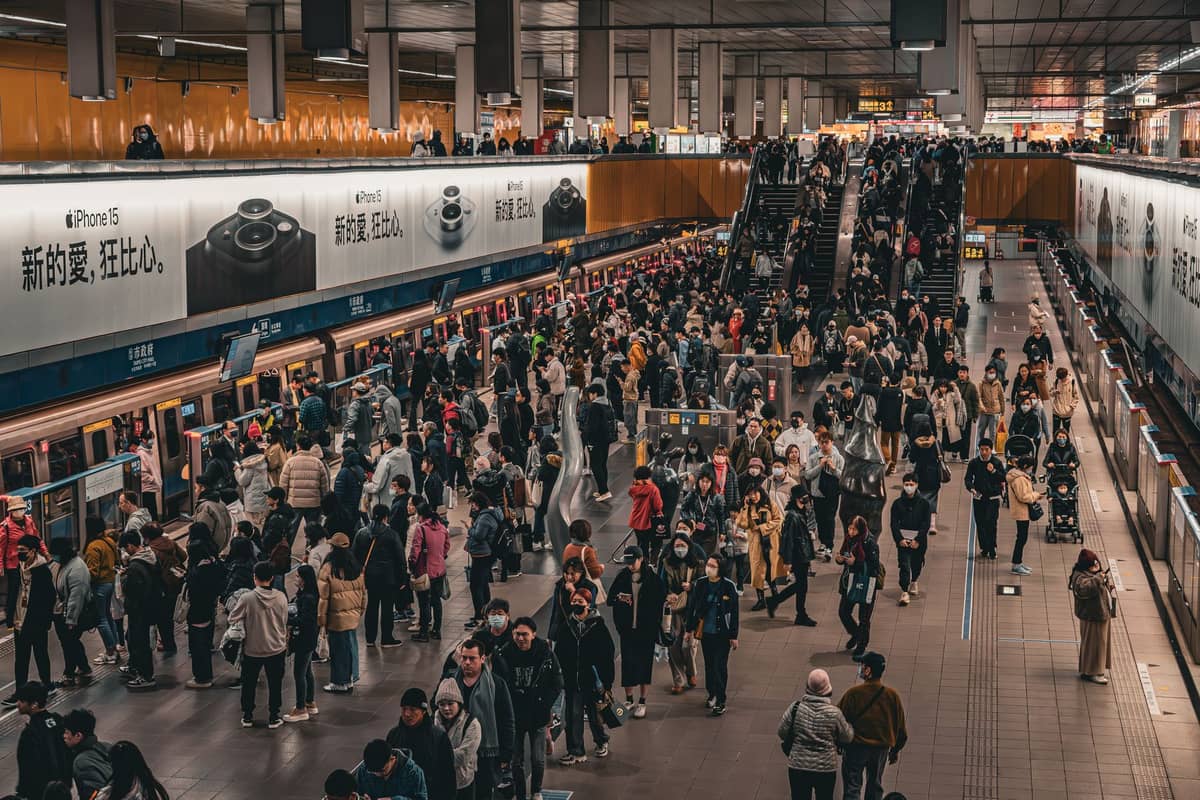 Überfüllter U-Bahnsteig in Beijing mit wartenden Menschen neben dem Zug und Rolltreppen in einer belebten unterirdischen Station.