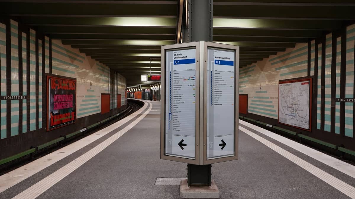 U-Bahn-Bahnsteig in Berlin mit Linienplänen, Fahrplanschildern und gefliesten Bahnhofswänden, die das lokale Nahverkehrssystem veranschaulichen.