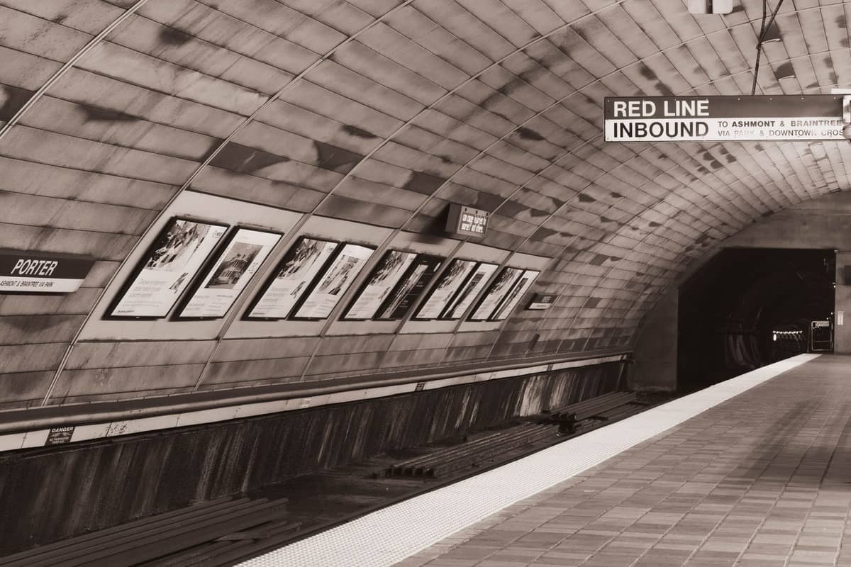 Ein unterirdischer MBTA Red Line U-Bahnsteig an der Porter Station in Boston, mit gewölbter Decke und übersichtlicher Beschilderung.