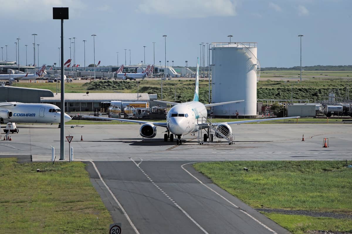 View of a commercial airplane on a taxiway at an airport in daylight with other planes and airport facilities in the background.