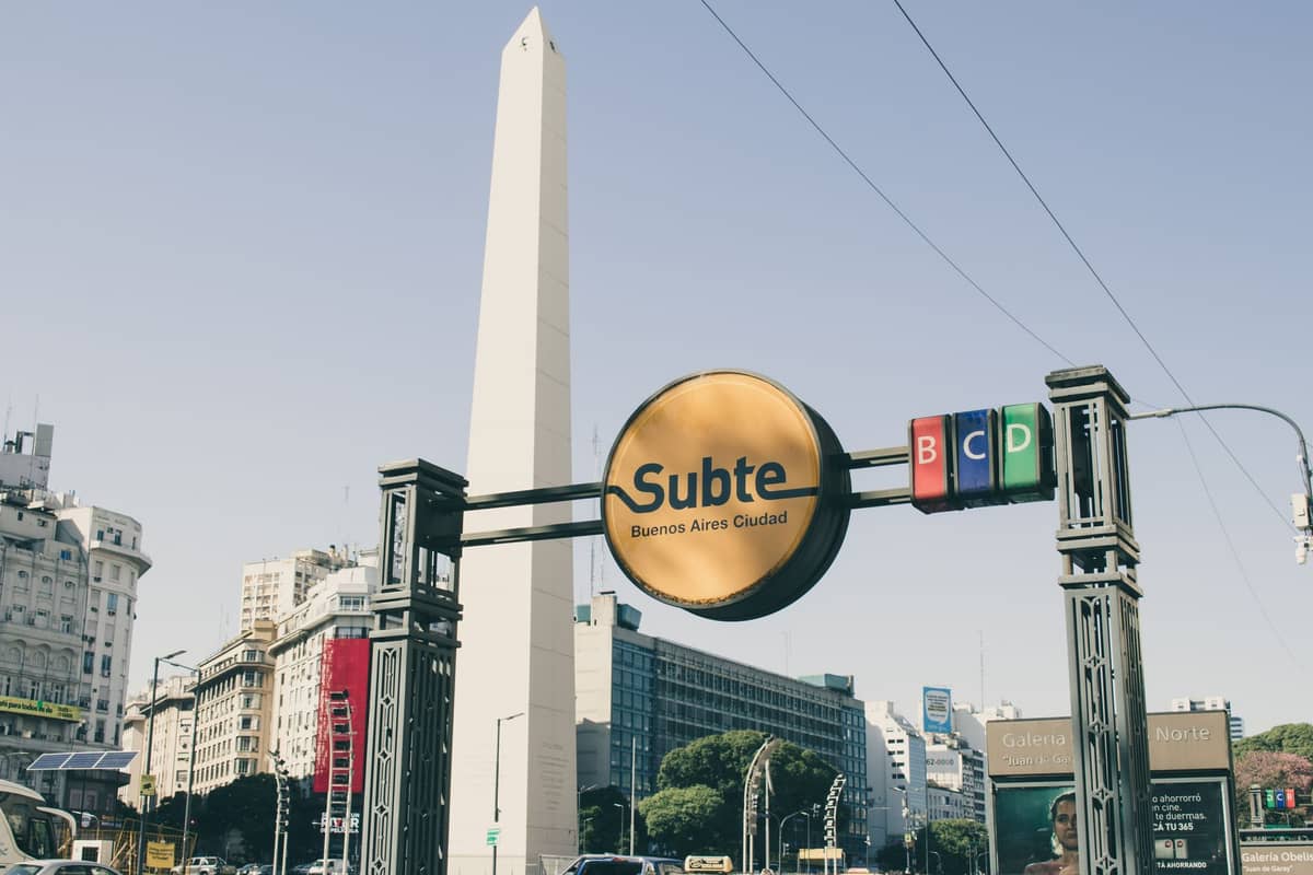 ทางเข้า Subte ของ Buenos Aires พร้อมป้าย Subte สีเหลืองและ Obelisco เป็นฉากหลังในวันที่แดดจัด