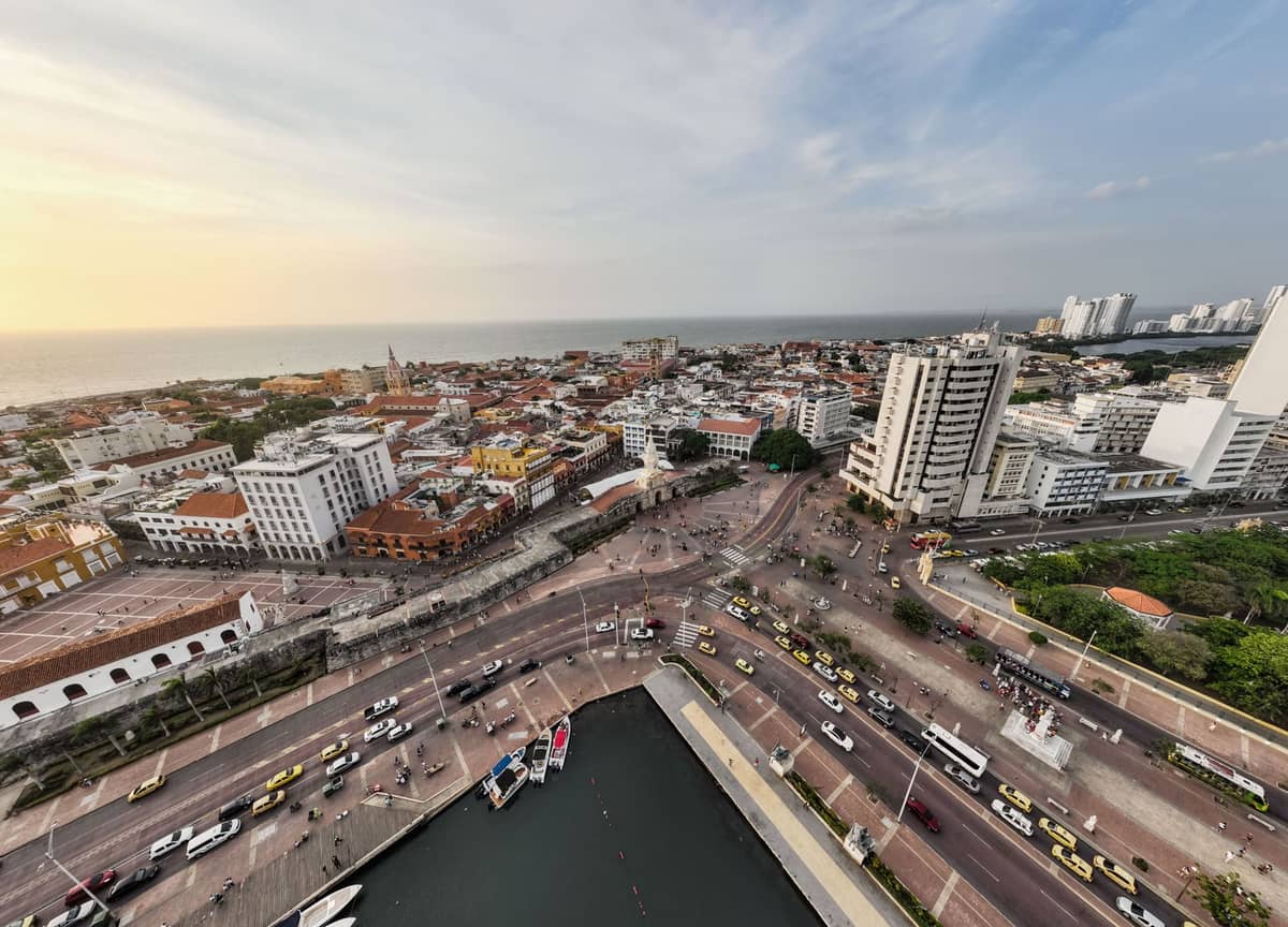Aerial view of Cartagena, Colombia showing historic city streets, yellow taxis, buses, pedestrians, and the cityscape by the waterfront.