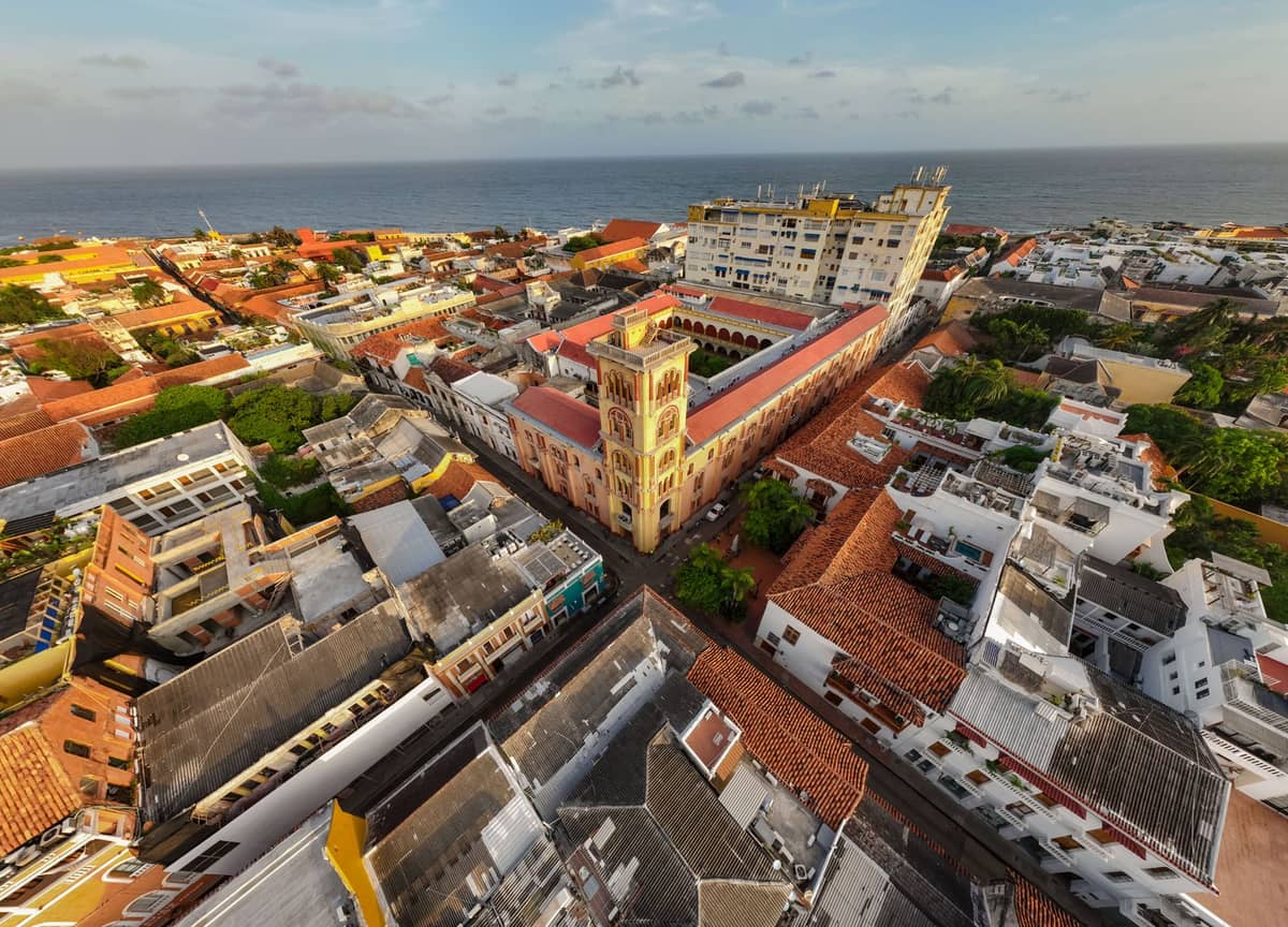 Aerial view of Cartagena's old town with colonial buildings, narrow streets, and the Caribbean Sea in the background.