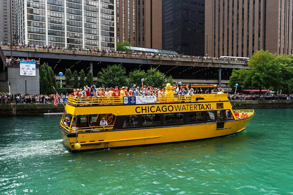 Chicago Water Taxi filled with passengers traveling on the Chicago River surrounded by tall downtown buildings.