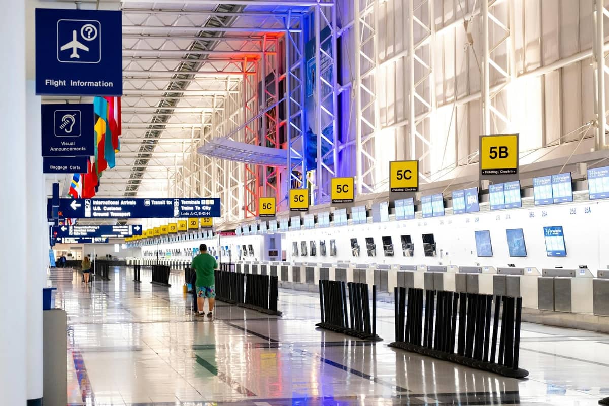 Wide interior view of a bright airport check-in hall in Chicago, with signage, international flags, and empty check-in counters.