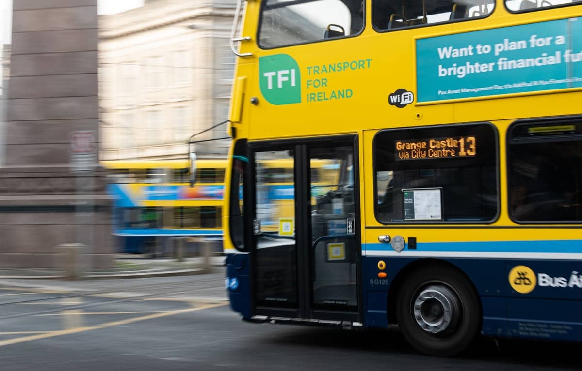 Nahaufnahme eines modernen gelb-blauen Dublin Bus auf den Stadtstraßen, mit Transport for Ireland-Beschilderung und sichtbaren Streckendetails.