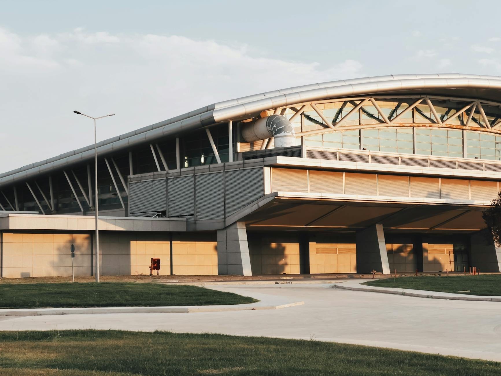 Vue extérieure d'un terminal d'aéroport moderne au crépuscule, avec un toit courbé et une large entrée, représentant probablement l'Aéroport de Dubrovnik.
