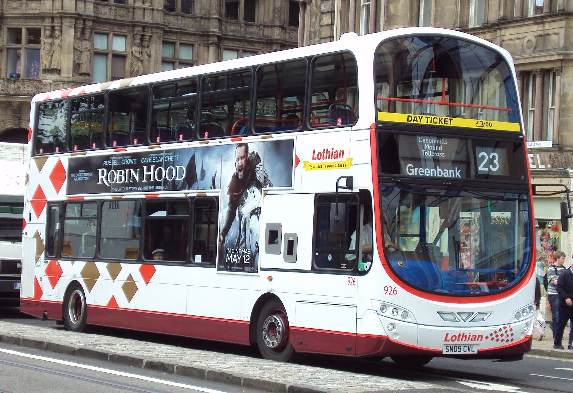 Ein Doppeldeckerbus von Lothian Buses in Edinburgh, deutlich beschriftet und auf einer Stadtstraße geparkt, mit historischen Steingebäuden im Hintergrund.