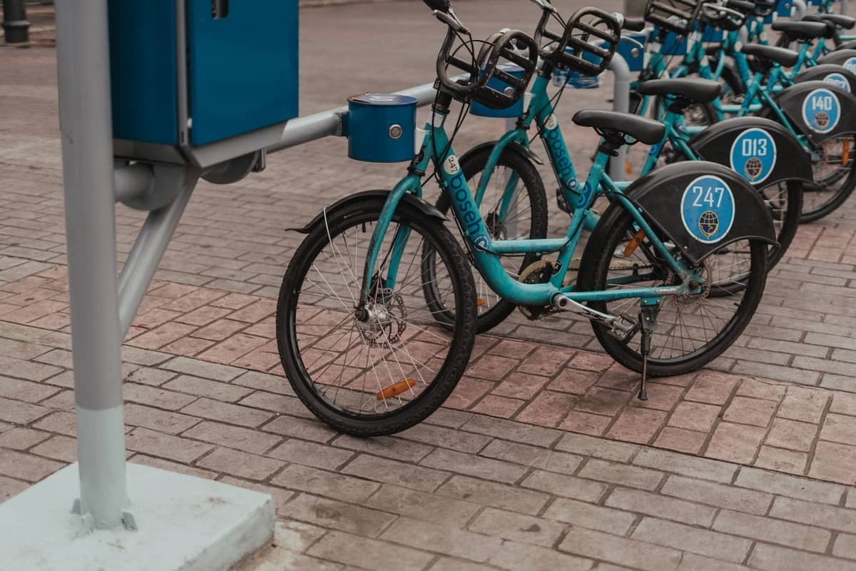 Reihe von öffentlichen MiBici-Fahrrädern, die an einer Station in Guadalajara auf einem Stadtbürgersteig angedockt sind, mit blauen Fahrrädern mit Identifikationsnummern.