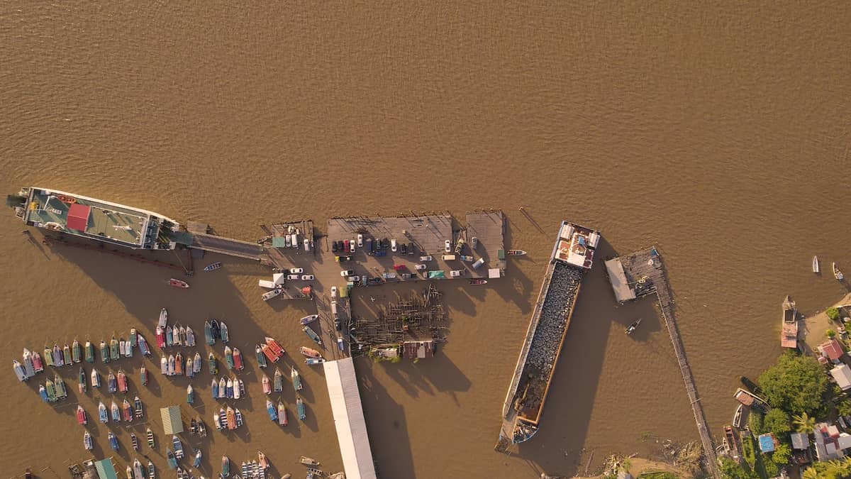 Vista aérea de un concurrido muelle fluvial con transbordadores y pequeñas embarcaciones atracadas, probablemente utilizado para transporte regional en el sur de Tailandia.