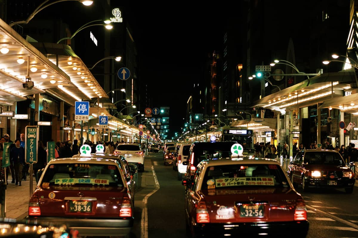 Kyoto street at night crowded with taxis and illuminated by city lights, showing active night transport options.