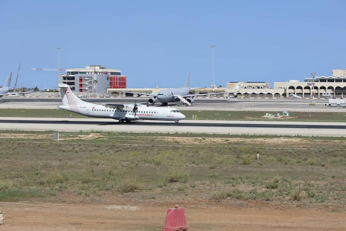 Cảnh đường băng của Sân bay Palma de Mallorca với các máy bay thương mại, tòa nhà sân bay và bầu trời trong xanh ở phía sau.