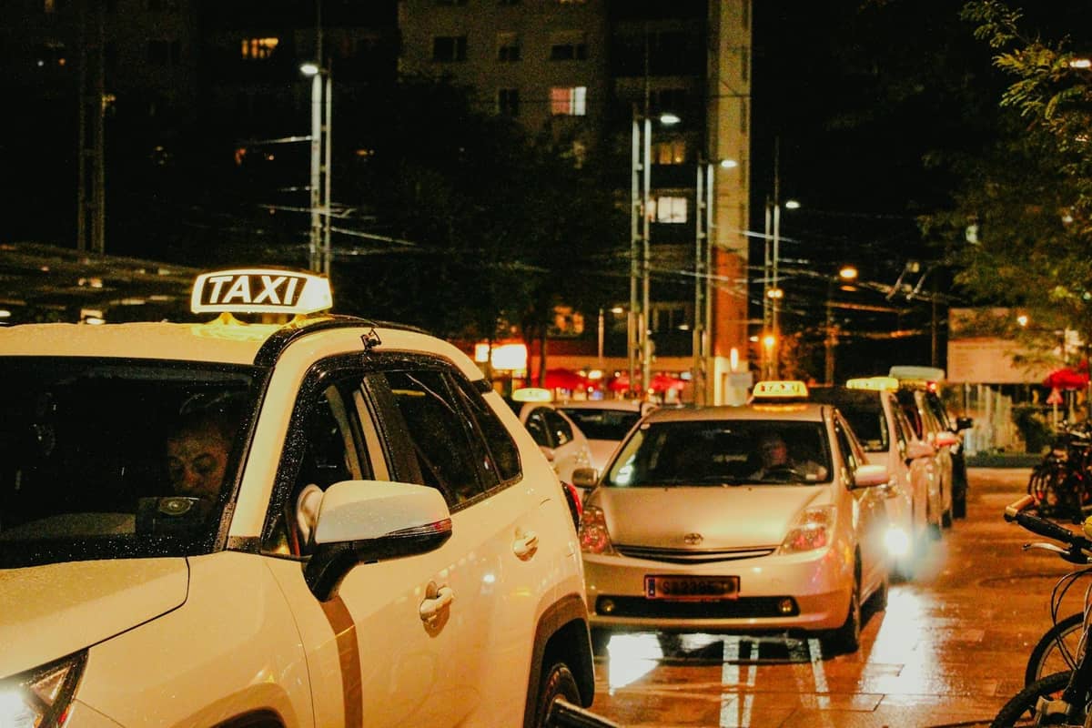 Hàng taxi vào ban đêm trên đường phố thành phố, hiển thị biển hiệu taxi và phông nền đô thị với ánh đèn.