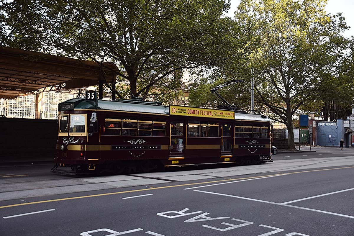 A vintage maroon and cream City Circle tram (Route 35) in Melbourne, traveling along a leafy city street, with the tram number and signage clearly visible.