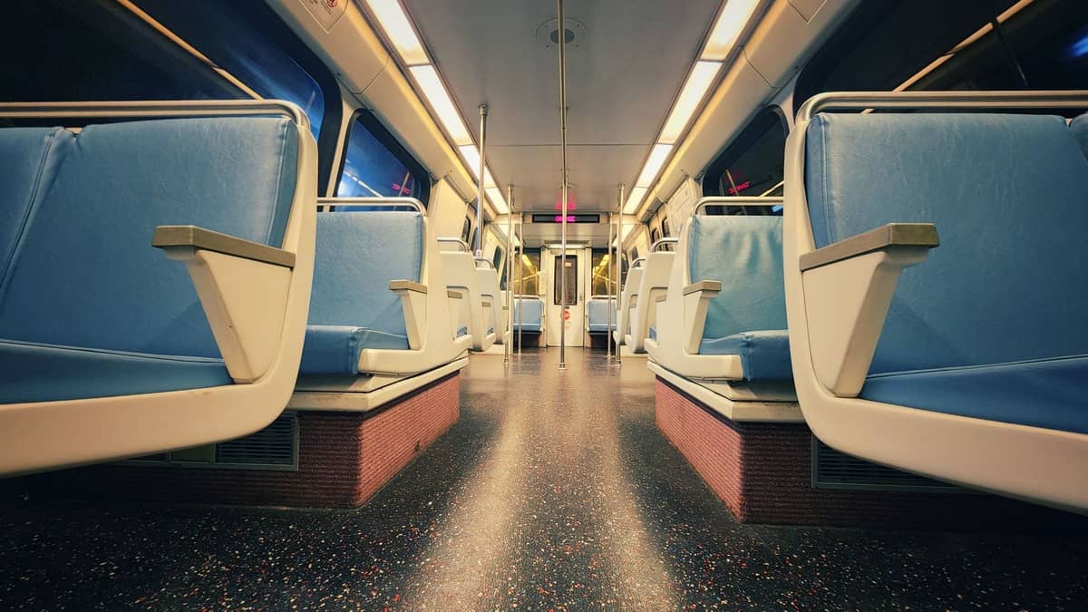 Interior view of an empty rapid transit rail car with blue seats and overhead lighting, resembling Miami Metrorail.