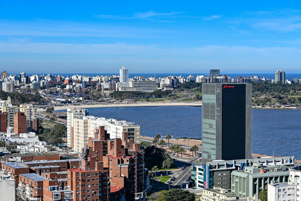 มุมมองทางอากาศของแนวชายฝั่ง Montevideo พร้อมย่านที่พักอาศัย อาคารสูง และถนนสายหลักที่ขนานไปกับชายฝั่งภายใต้ท้องฟ้าสีฟ้าสดใส