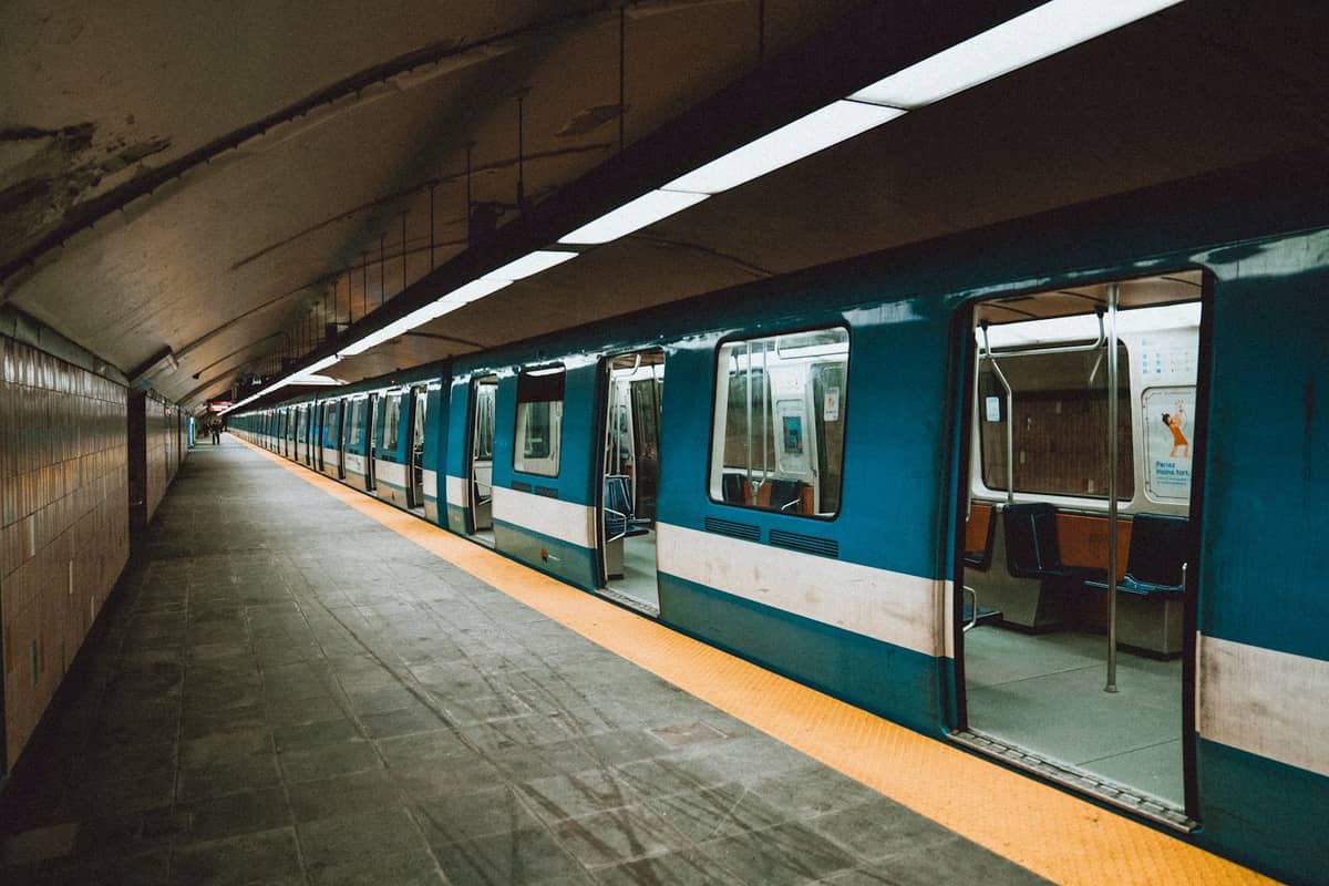Montreal Metro station platform with classic blue STM train, open doors, and yellow safety line on the ground.