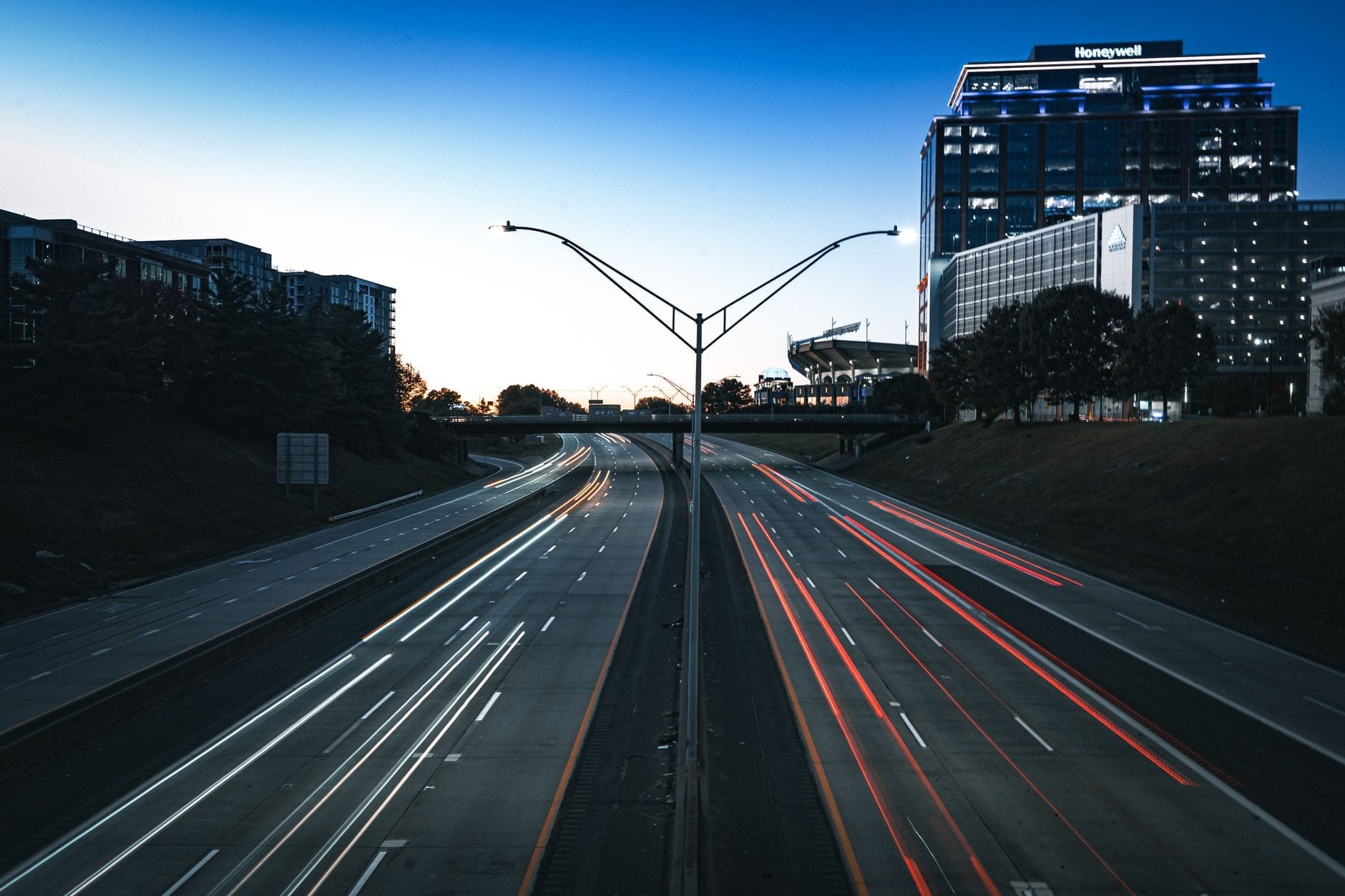 Autopista urbana al atardecer en Nashville con edificios modernos y rastros de luces de tráfico a ambos lados de la carretera.
