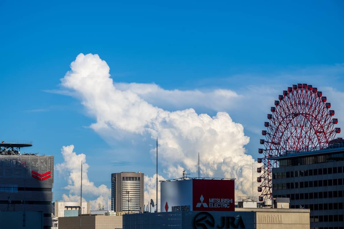 Urban skyline in Umeda, Osaka, featuring the red HEP Five Ferris Wheel and recognizable commercial buildings under a blue sky.