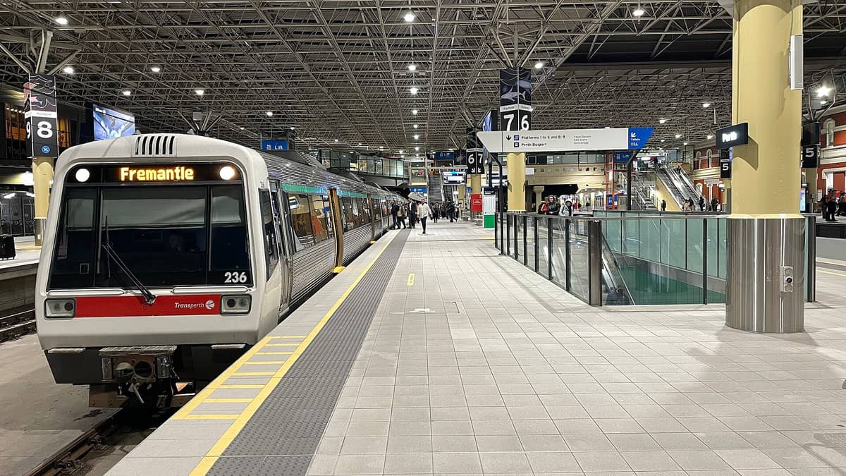 Transperth-Zug mit Ziel Fremantle an einem Bahnsteig in der Perth Station, mit gut sichtbarer Beschilderung und Fahrgästen auf dem Bahnsteig.