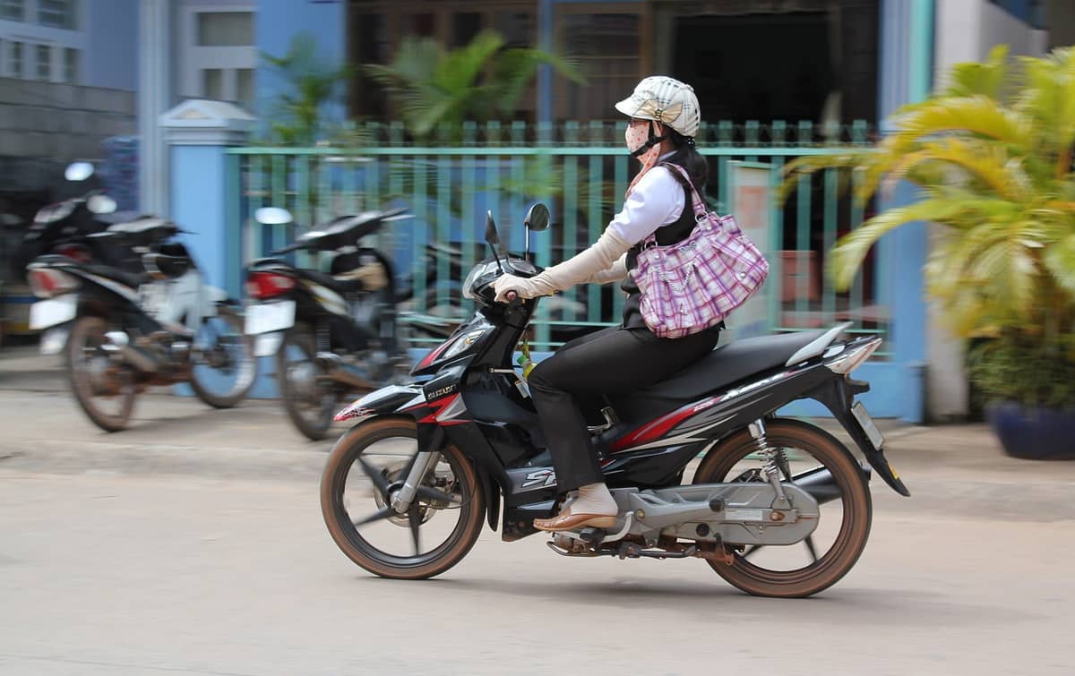 Motorbike rider on a street in Phu Quoc wearing helmet and face mask, typical local transport scene