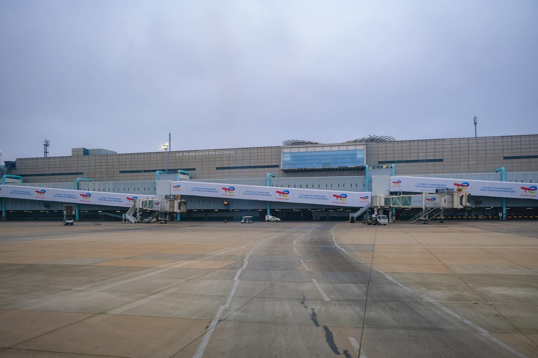 Exterior view of Phuket International Airport terminal with multiple jet bridges on a cloudy day