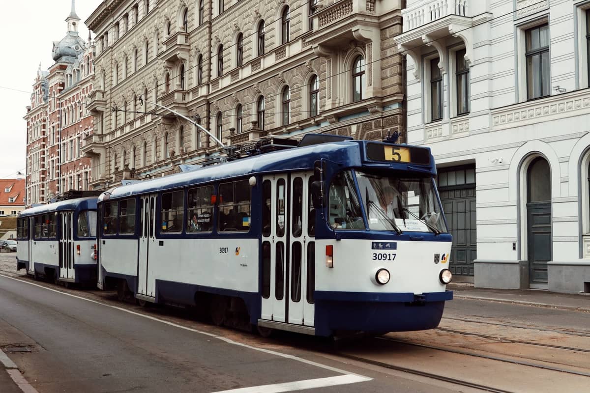 Eine Rigaer Straßenbahn fährt durch die historische Altstadt, flankiert von klassischen Steinfassaden und typischen Straßendetails.
