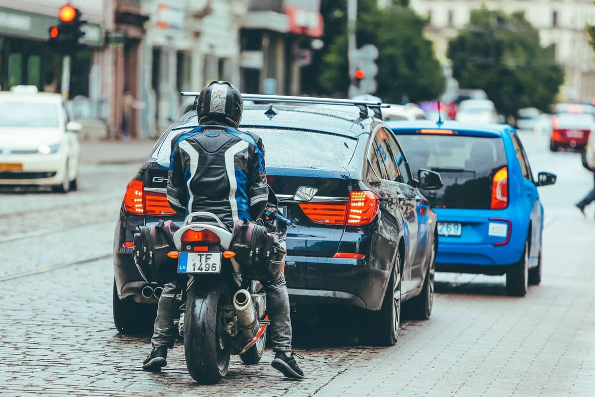 Städtische Straßenszene in Riga mit Autos, einem Motorrad und Stadtgebäuden; veranschaulicht Optionen für privaten Transport und Taxis.