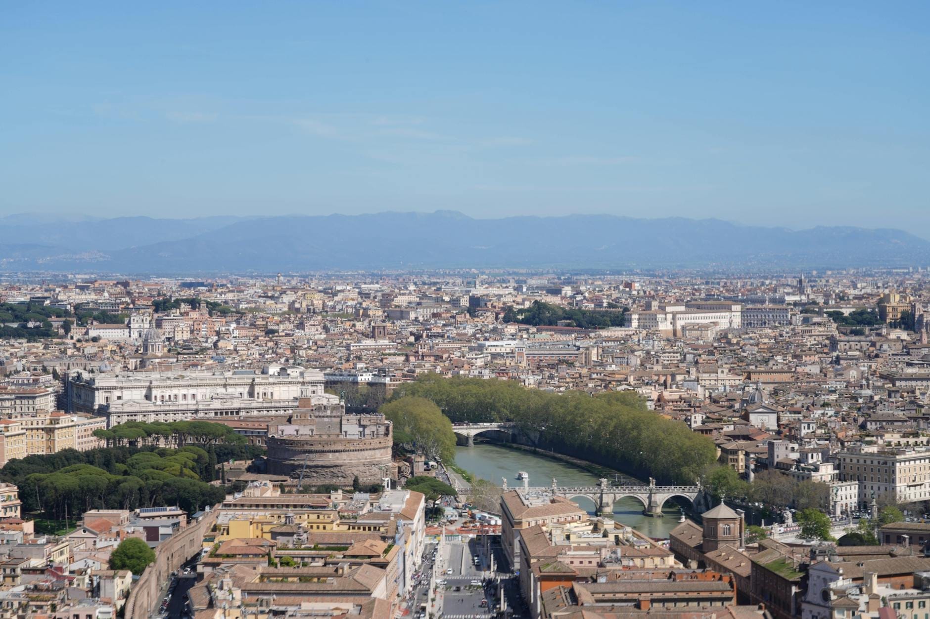 Wide aerial view of Rome showing the Tiber River, Castel Sant'Angelo, major landmarks and the urban layout of the city.