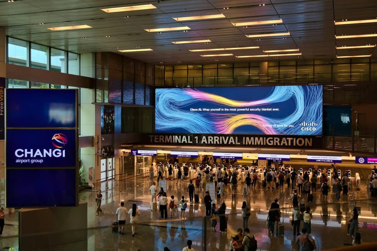 Arrival hall at Changi Airport Terminal 1 with people, immigration counters, and Changi signage visible.