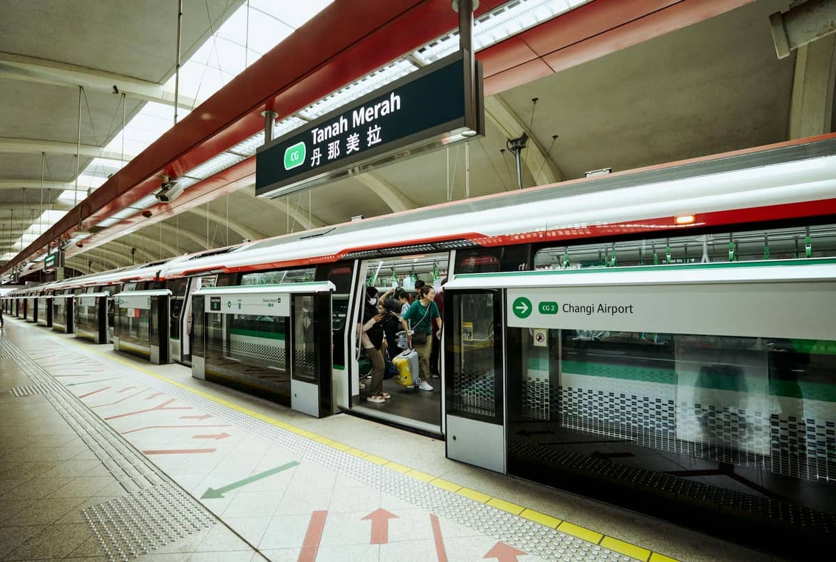 Singapore MRT station platform at Tanah Merah, with train doors open, passengers boarding, and clear MRT signage visible.
