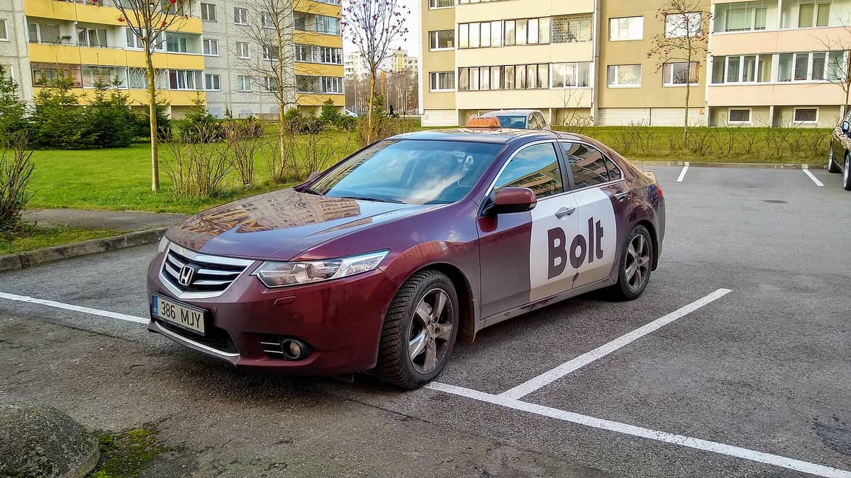 Taksi bermerek Bolt yang diparkir di kawasan perumahan Tallinn, menampilkan logo Bolt dan pelat nomor Estonia dengan jelas.