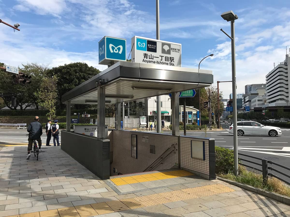 Outdoor view of Aoyama-itchome Tokyo Metro entrance with signage, stairs descending, and city street in background.
