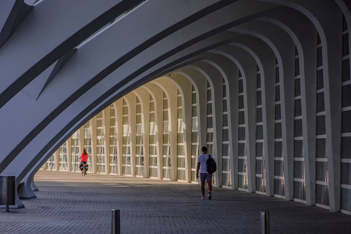 Un ciclista pedalea bajo los característicos arcos blancos de la Ciudad de las Artes y las Ciencias de Valencia, un lugar popular a lo largo de la ruta ciclista del parque del Turia.