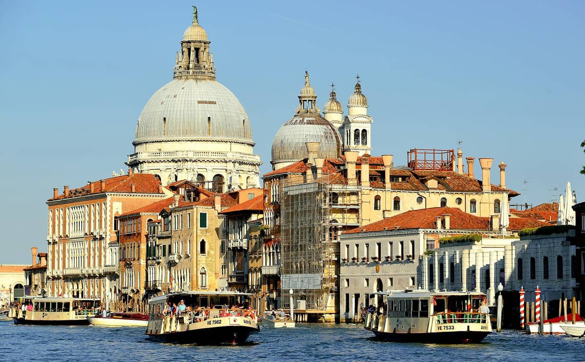 Mehrere Vaporetto-Wasserbusse auf dem Canal Grande in Venedig, mit der Basilika Santa Maria della Salute und historischen Gebäuden im Hintergrund.