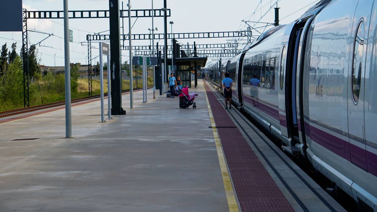 รถไฟความเร็วสูง AVE สมัยใหม่จอดรอบนชานชาลากลางแจ้งพร้อมผู้โดยสารอยู่ใกล้เคียงในวันที่แดดจัด