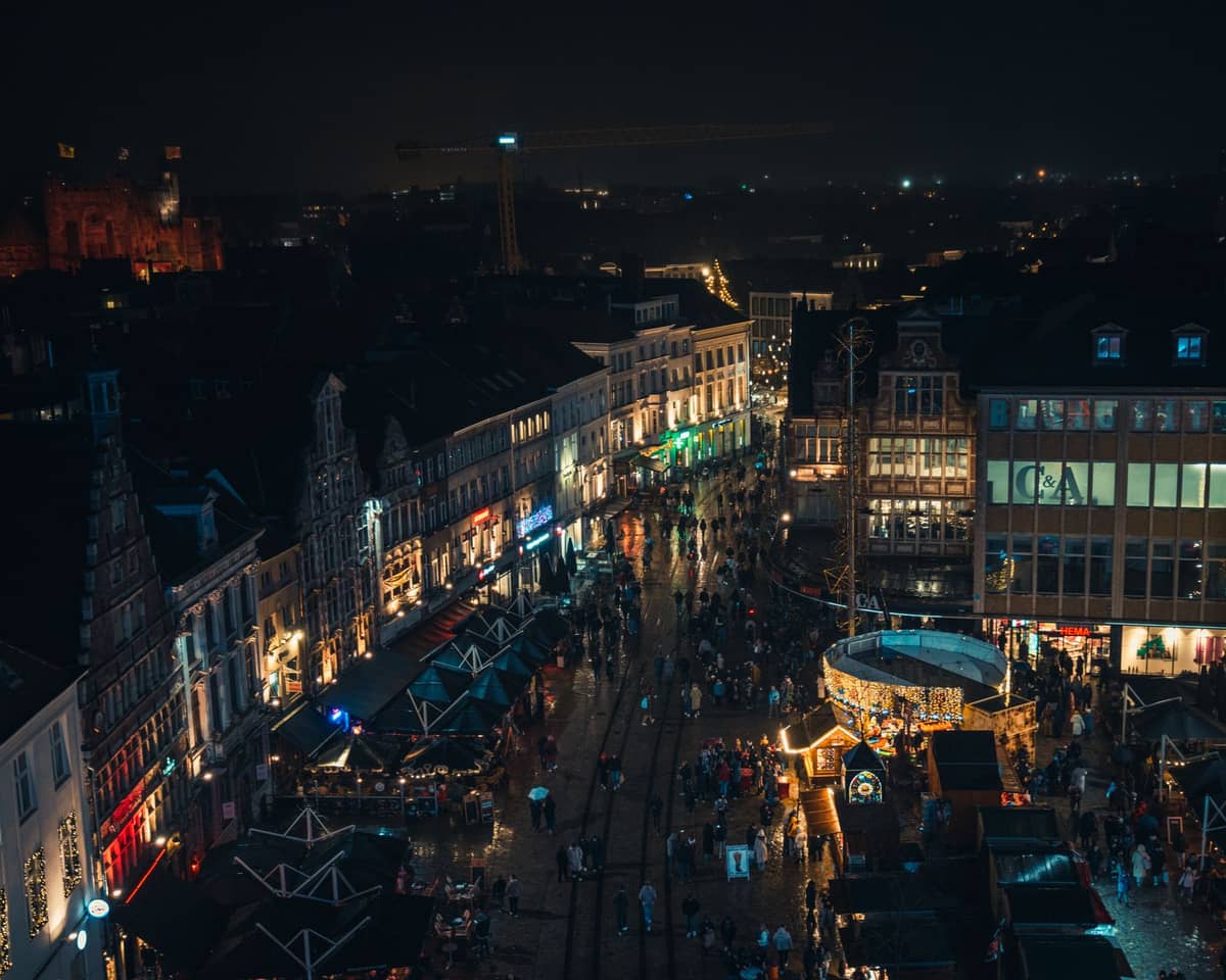 Aerial night view of Ghent city center with illuminated buildings, lively crowds, and classic Flemish gabled architecture representing Ghent nightlife.