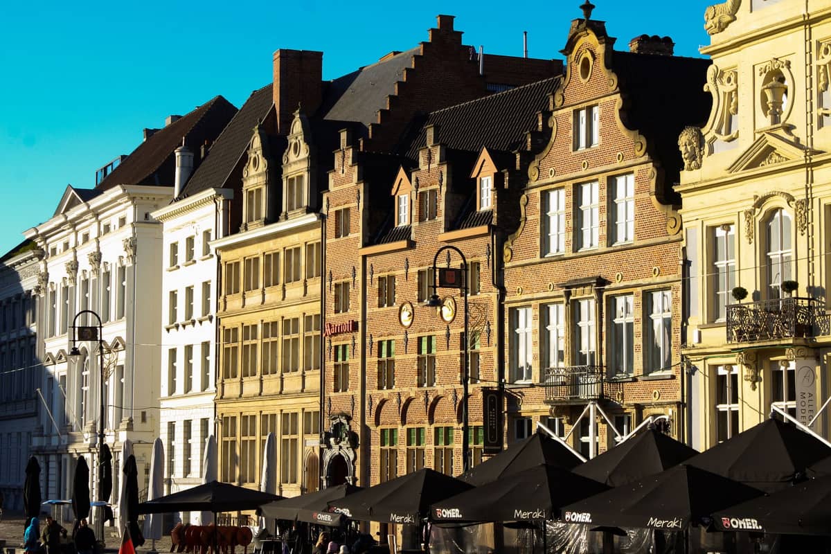 Row of historic gabled buildings with outdoor cafes and terraces in a lively street scene in Ghent, Belgium