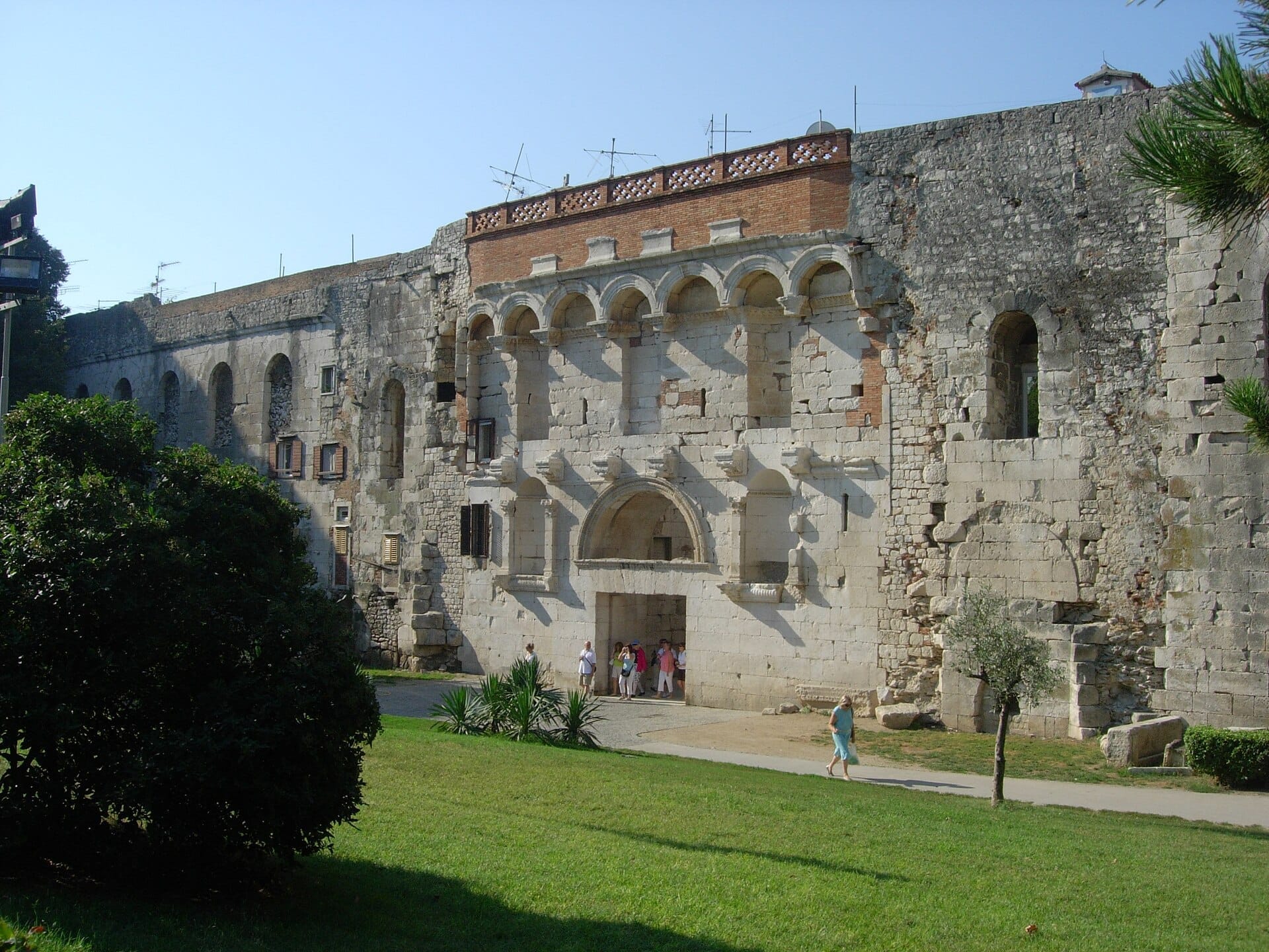 ประตูทองของพระราชวัง Diocletian ใน Split ประเทศโครเอเชีย พร้อมซุ้มหินขนาดใหญ่ กำแพงโบราณ และนักท่องเที่ยวที่กำลังเดินผ่านเข้าไปด้านล่าง