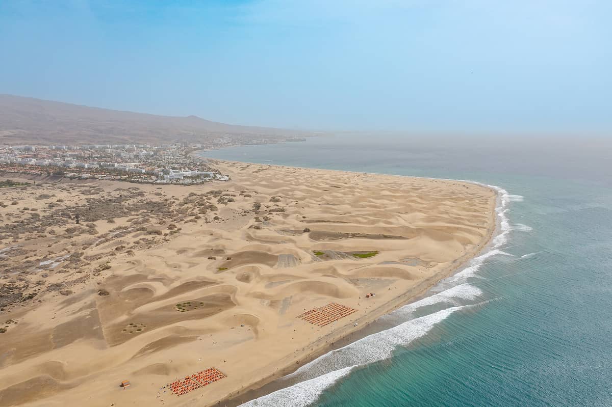 Вид с воздуха на Maspalomas с песчаными дюнами, пляжем, океаном и близлежащими курортами, демонстрирующий близость зон «всё включено» к береговой линии.