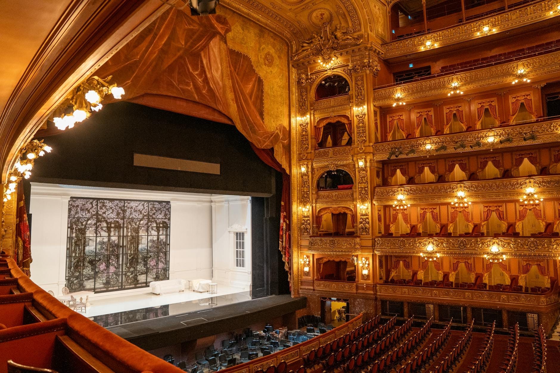 Interior view of Gran Teatre del Liceu showing its ornate golden balconies, red velvet seats, and an empty stage set for a performance.