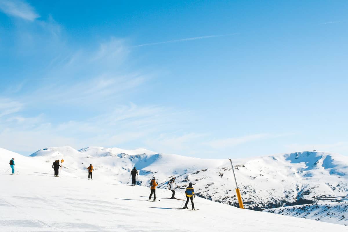 นักสกีบนลาดเขาที่ปกคลุมด้วยหิมะของเทือกเขา Sierra Nevada ภายใต้ท้องฟ้าสีฟ้า แสดงให้เห็นกิจกรรมสกีในฤดูหนาว